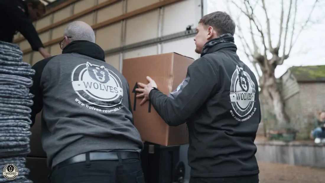 The Wolves team carefully carrying a wrapped box out to the van for storage — Wolves Storage Sussex serving Ashington