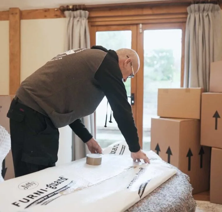 A Wolves Storage Sussex packer taping Furni-guard protection around furniture &mdash; Wolves Storage Sussex serving Cowfold